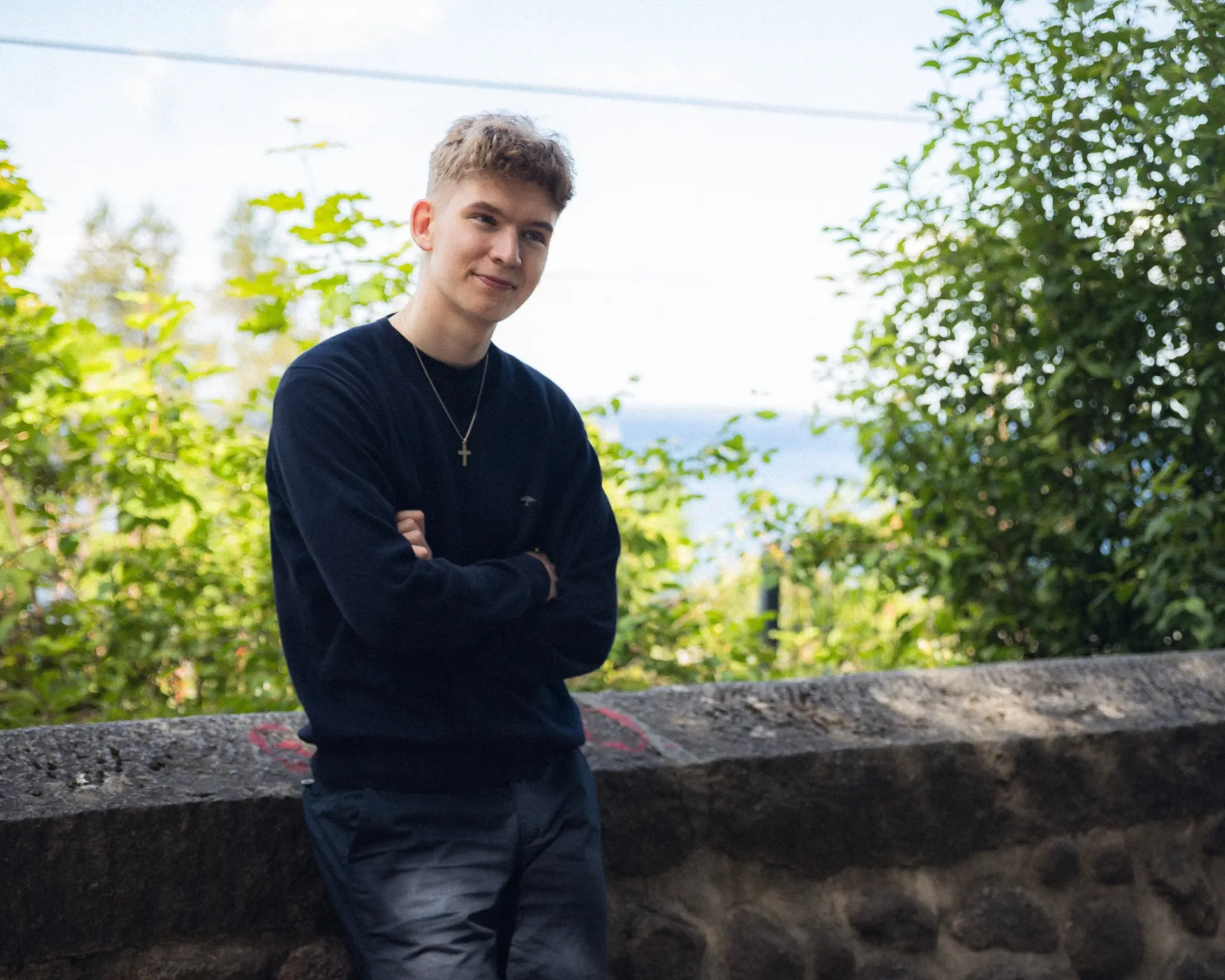 Eelis Viskari standing outdoors by a stone wall
